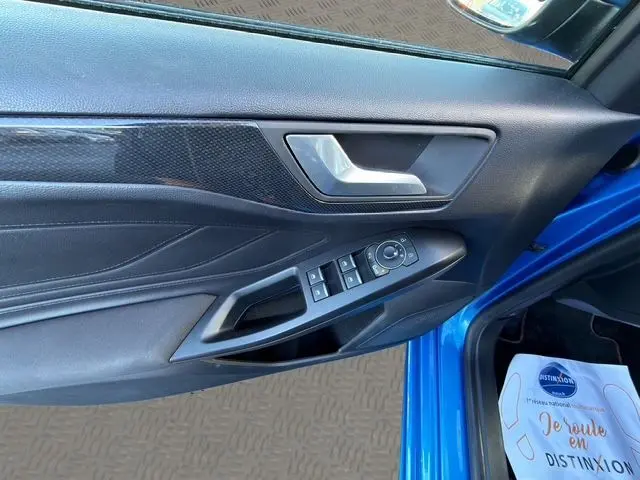 Vue rapprochée de la porte avant gauche bleue d'une Ford Focus 1.5 EcoBoost 150ch ST-Line 2022 avec commandes électriques.