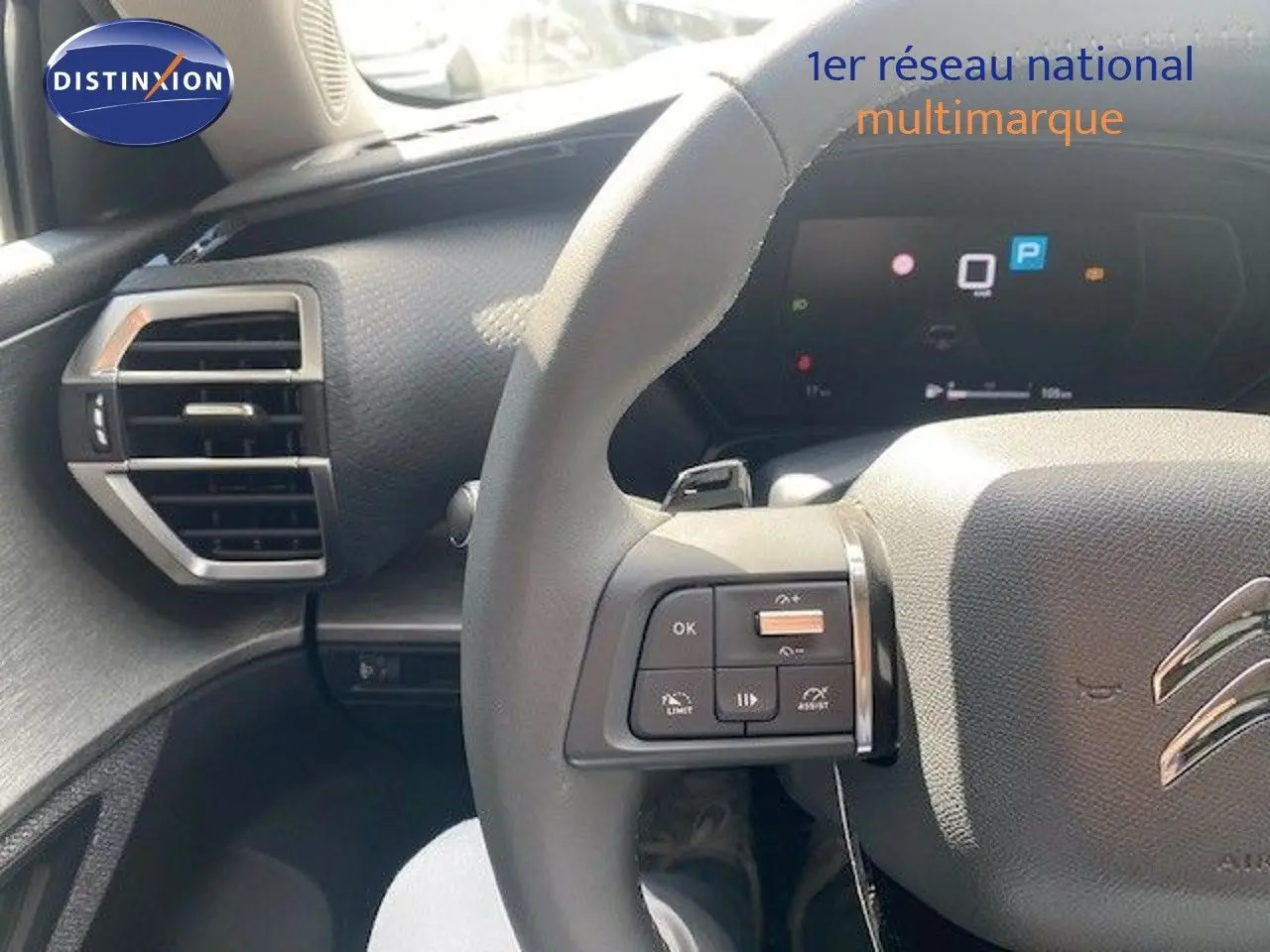 Vue rapprochée du volant gris avec commandes intégrées et tableau de bord numérique du Citroën C5 X 2023.