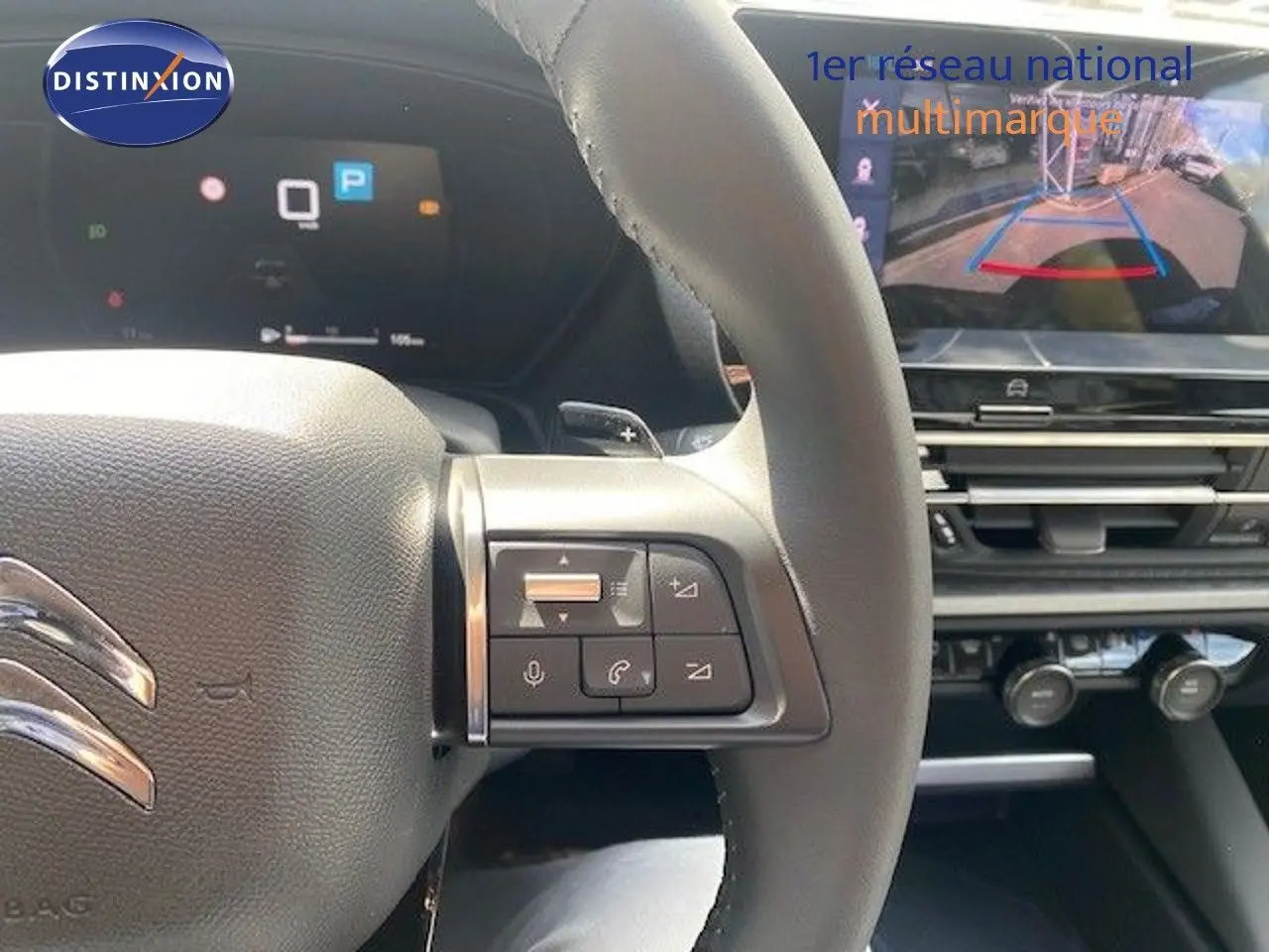 Vue intérieure centrée sur le volant gris noir de la Citroën C5 X 2023 avec écran de caméra de recul et commandes au volant.