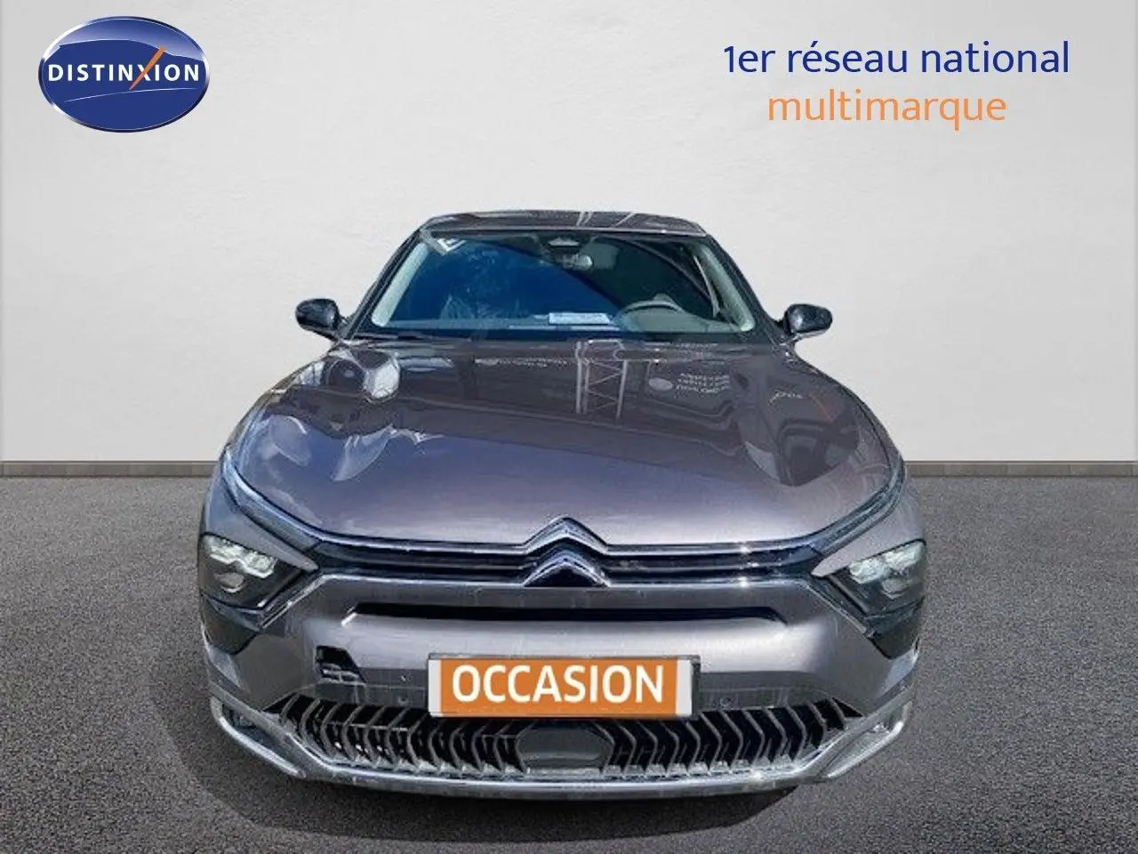 Vue frontale d'une Citroën C5 X gris platinium métal 2023 avec calandre distinctive et phares LED allumés.