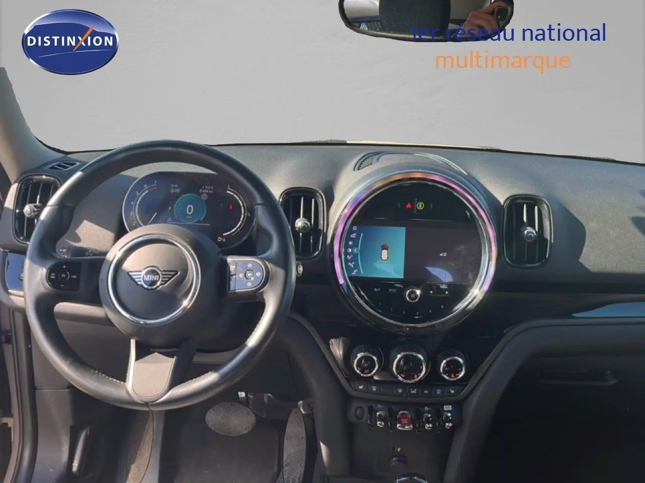 Vue intérieure avant du tableau de bord et volant d'une MINI Countryman Cooper 2023 avec écran central rond et finitions noires.
