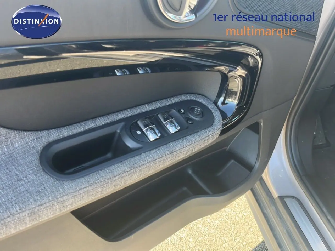 Détail de la porte avant gauche de la MINI Countryman 2023 en Rooftop Grey, avec commandes de vitres et tissu gris.