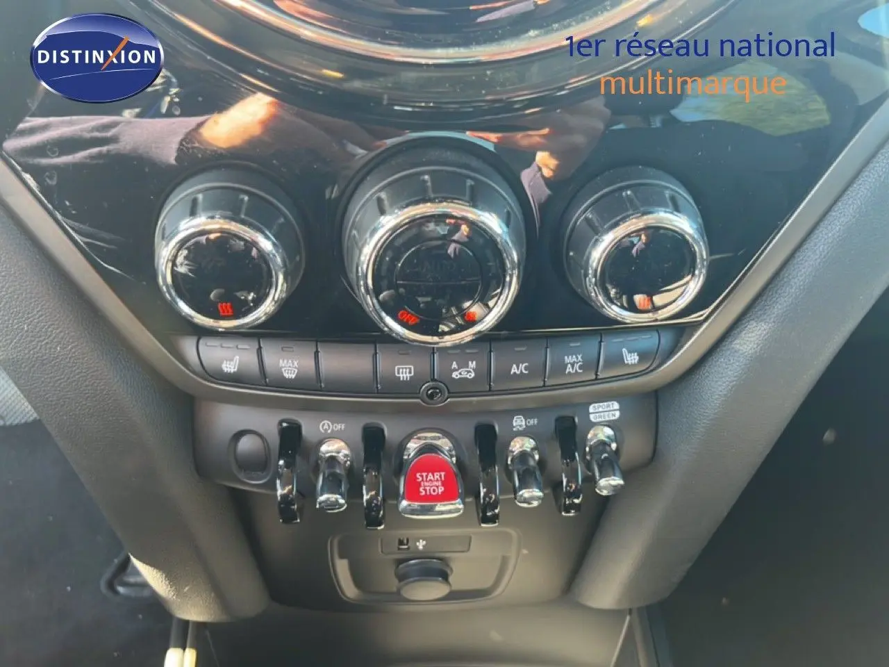Vue rapprochée de la console centrale du MINI Countryman 2023, mettant en valeur les commandes de climatisation et le bouton start/stop rouge.