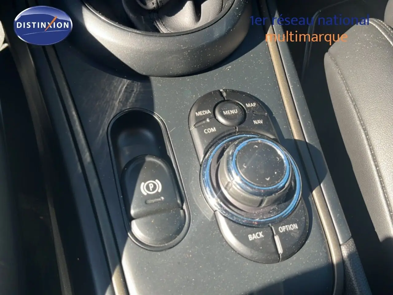 Gros plan sur la console centrale noire du MINI Countryman Cooper 2023, avec molette de commande et frein à main électrique.