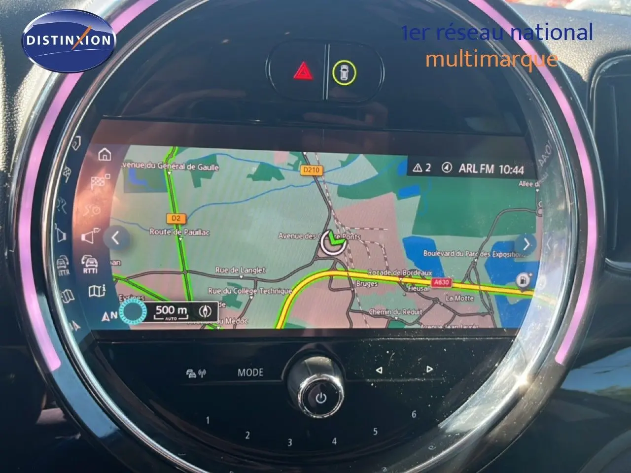Vue rapprochée de l’écran central rond du MINI Countryman gris, affichant la navigation GPS avec éclairage LED violet.