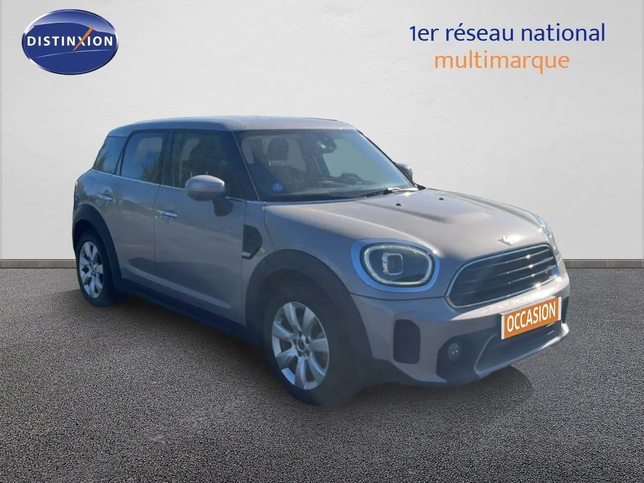 Vue 3/4 avant d'une MINI Countryman Cooper grise rooftop, avec calandre noire et jantes argentées.