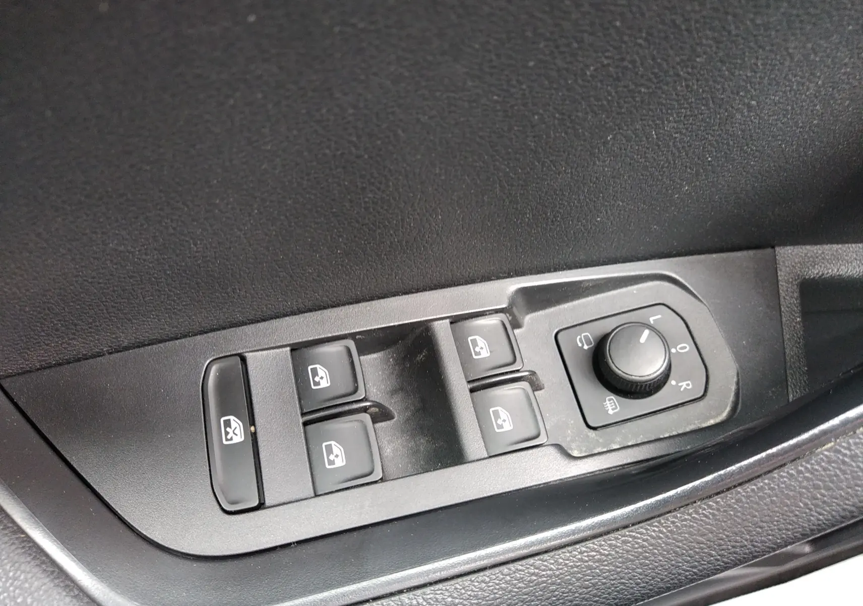 Gros plan sur les commandes des vitres et des rétroviseurs côté conducteur d'un Skoda Karoq gris 2021.