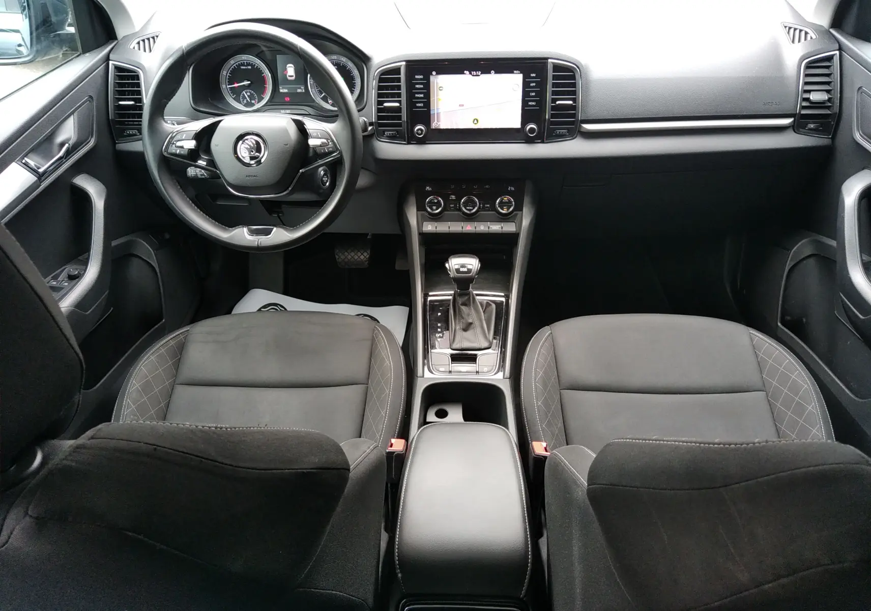 Vue intérieure avant du Skoda Karoq gris 2021, avec tableau de bord moderne, écran tactile et volant multifonction.
