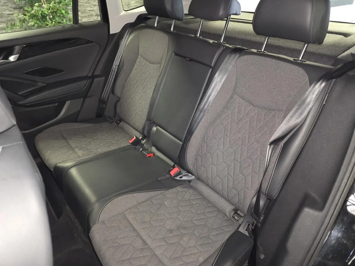 Vue intérieure arrière du Volkswagen Tiguan 2025 noir, montrant la banquette en tissu gris avec motifs géométriques.