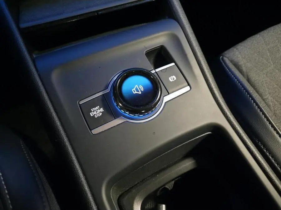 Gros plan sur la console centrale noire du Volkswagen Tiguan 2025, avec bouton start/stop et frein à main électronique.