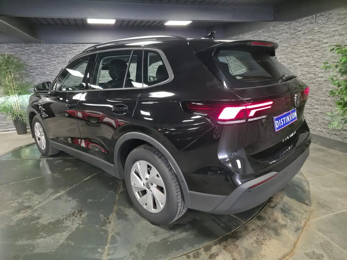 Volkswagen Tiguan noir 3/4 arrière droit en intérieur, feux arrière allumés et jantes alliage 17 pouces.