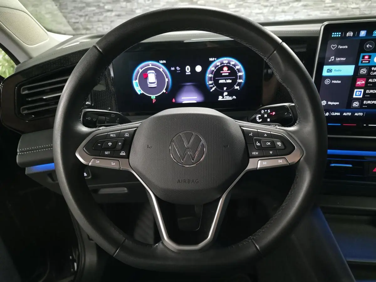 Vue rapprochée du volant en cuir noir du Volkswagen Tiguan 2025 avec tableau de bord numérique et écran tactile central.