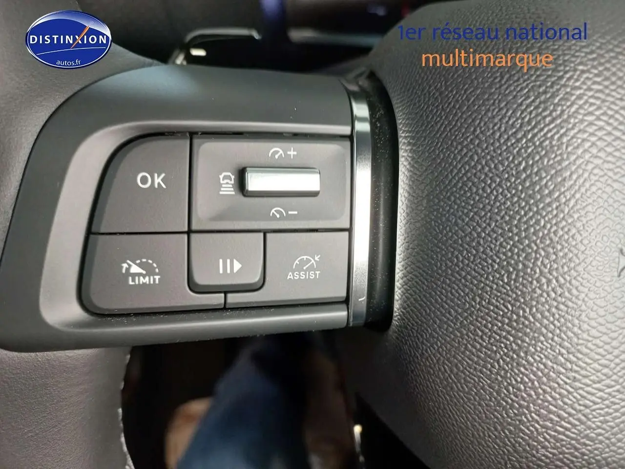 Gros plan sur les commandes de régulateur de vitesse au volant cuir noir du Citroën C4 X gris platinium 2023.