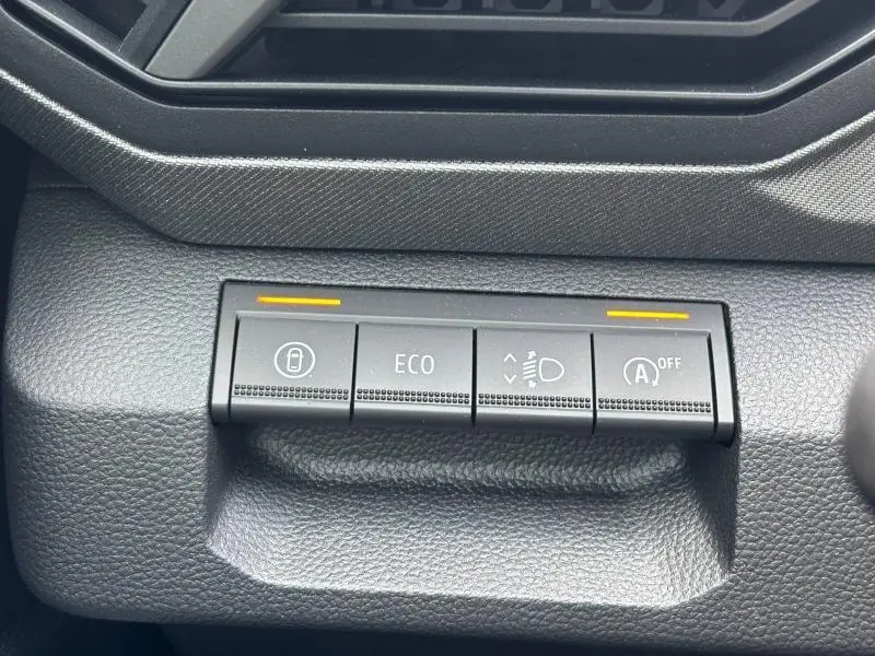 Gros plan sur les boutons de commande du mode ECO et des phares dans le tableau de bord noir du Dacia Bigster blanc 2025.