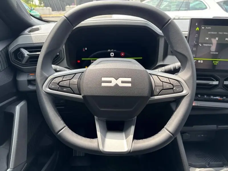 Vue rapprochée du volant multifonction noir du Dacia Bigster 2025 avec tableau de bord numérique et écran tactile latéral.