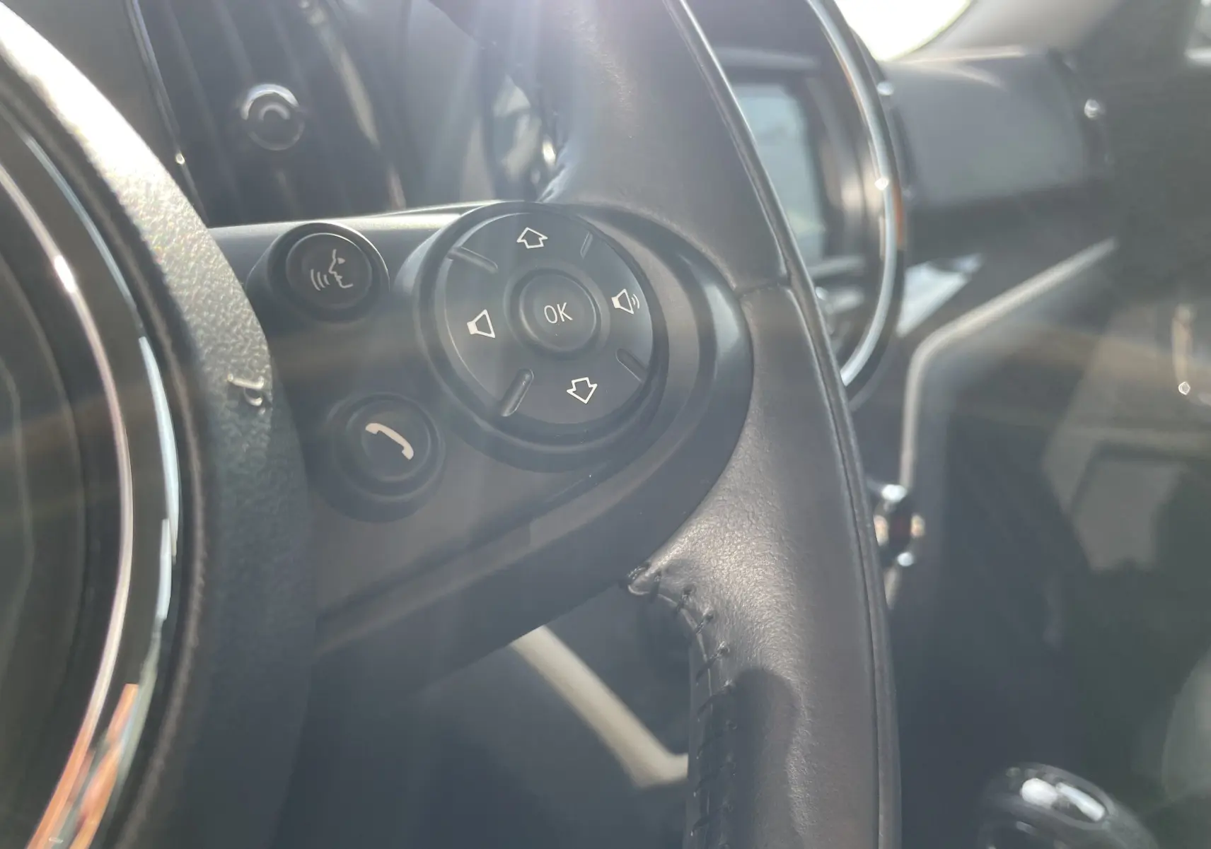 Gros plan sur les commandes du volant côté gauche du MINI Countryman F60 hybride gris Moonwalk, avec boutons multifonctions visibles.