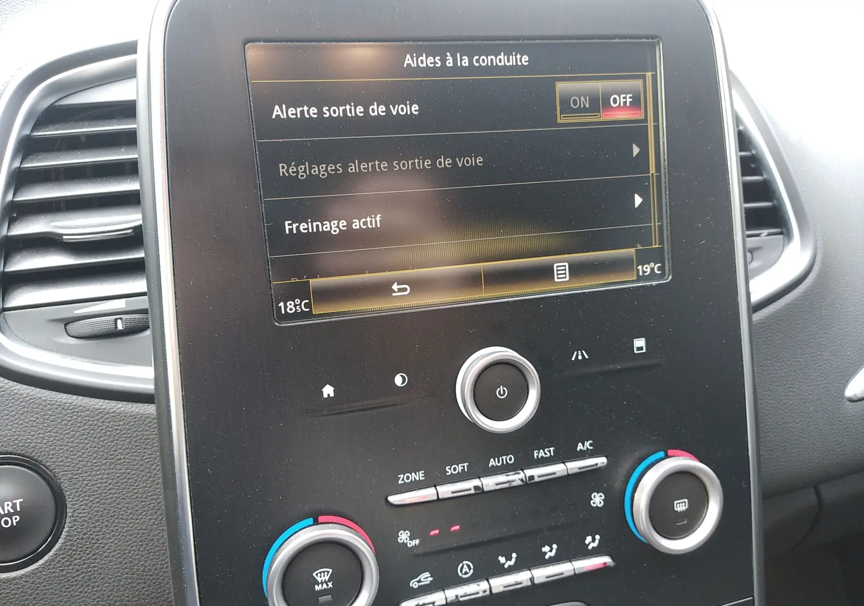 Écran tactile central du tableau de bord du Renault Grand Scenic IV brun, affichant les aides à la conduite et la climatisation.