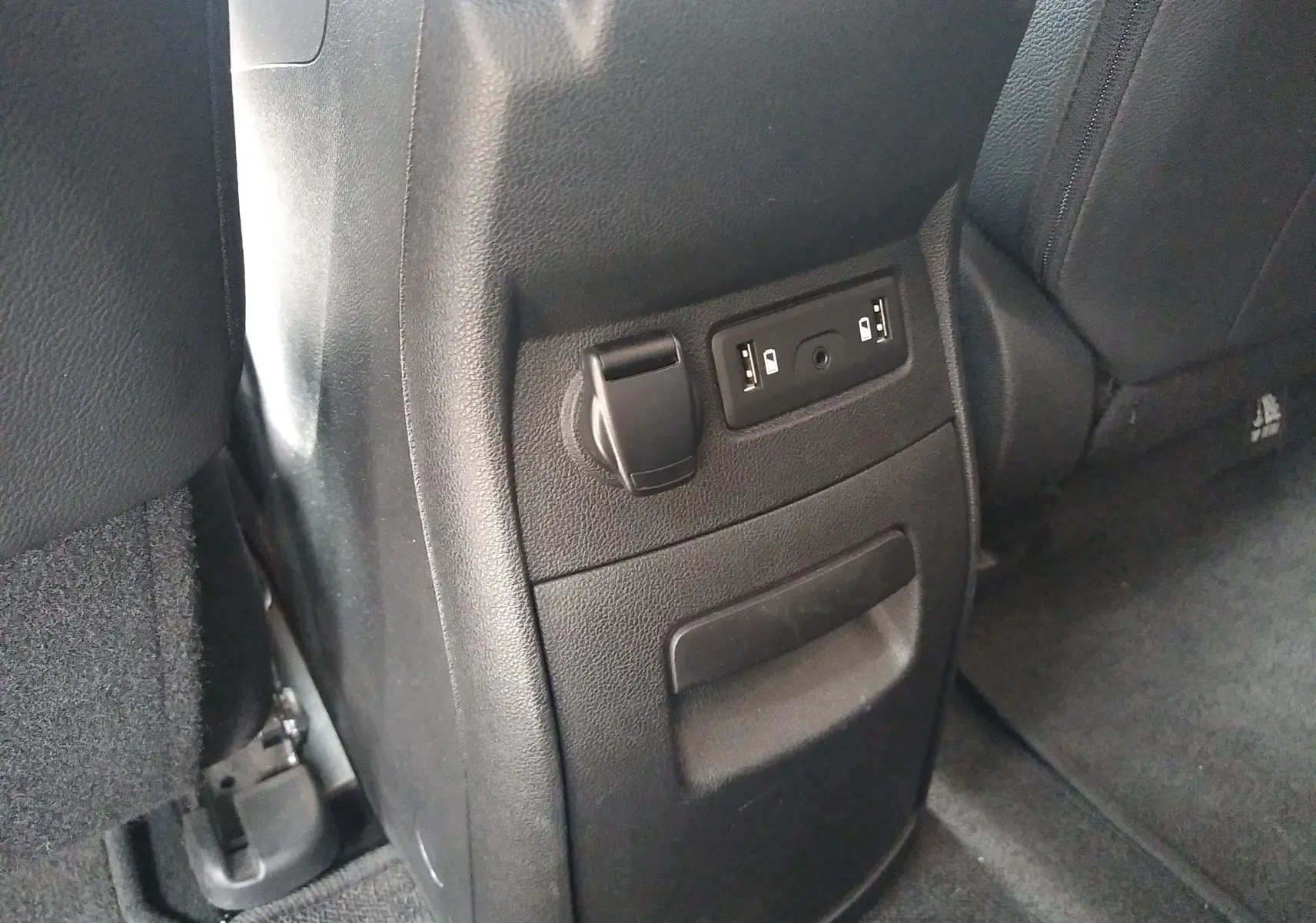 Prise USB et prise 12V en gros plan sur la console arrière d'un Renault Grand Scenic brun vison métal.