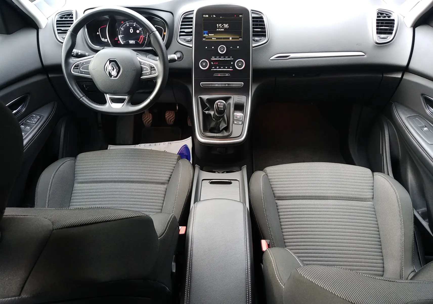 Vue intérieure avant du Renault Grand Scenic IV avec volant multifonction, console centrale tactile et sièges tissu gris.