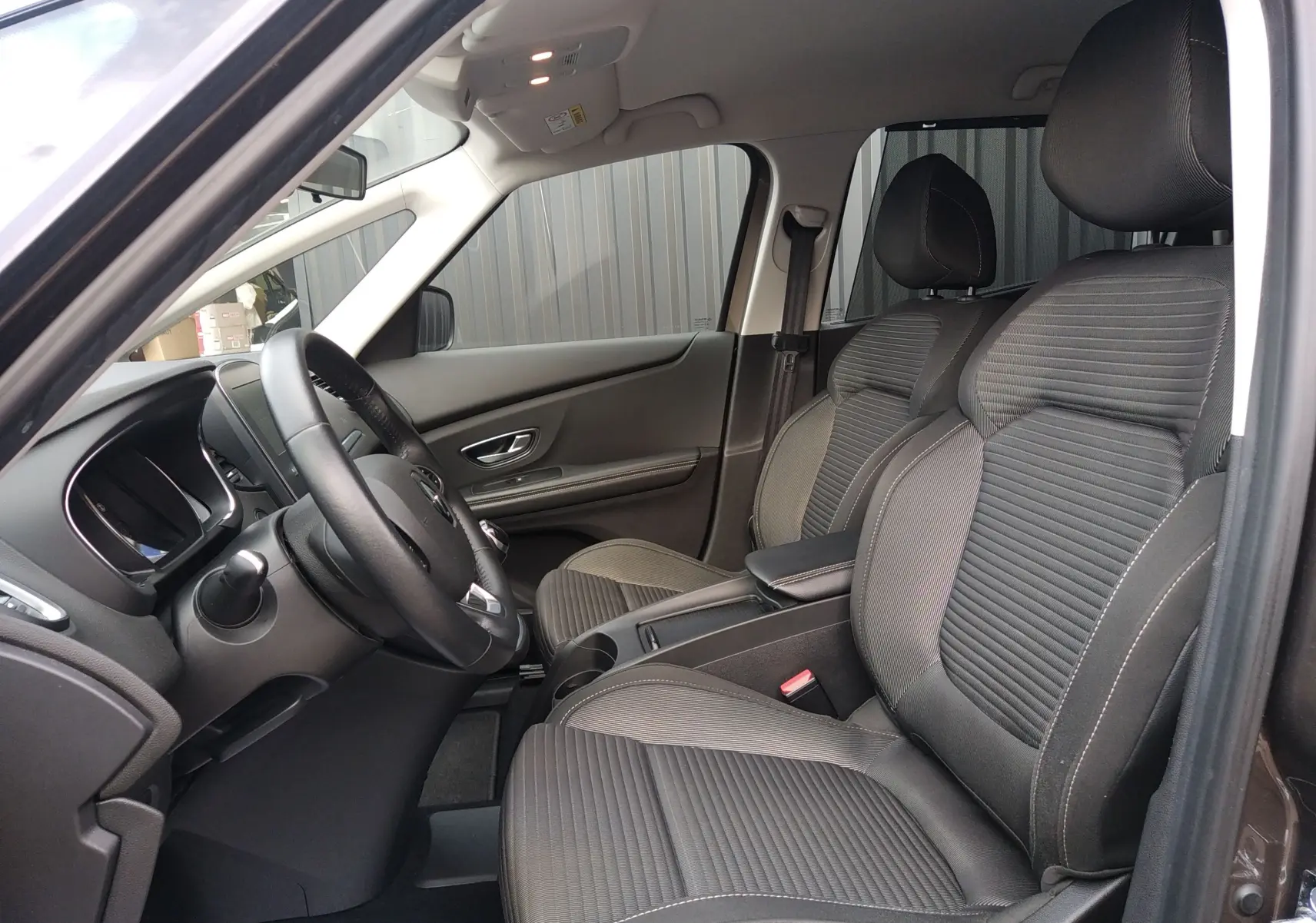 Vue intérieure côté conducteur du Renault Grand Scenic IV 2018, sièges tissu gris et tableau de bord sobre.