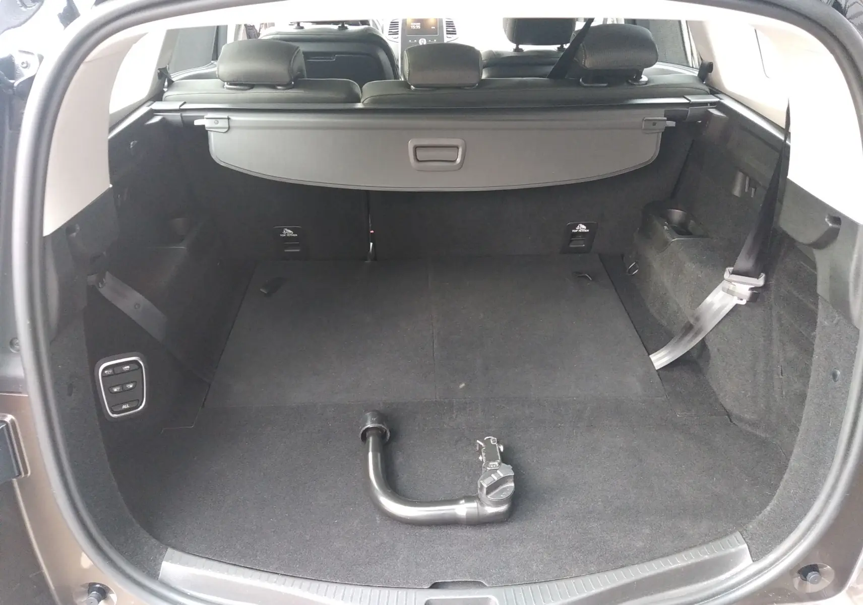 Coffre ouvert d'un Renault Grand Scenic brun vison métal, vue arrière montrant l'intérieur spacieux et la barre d'attelage amovible.
