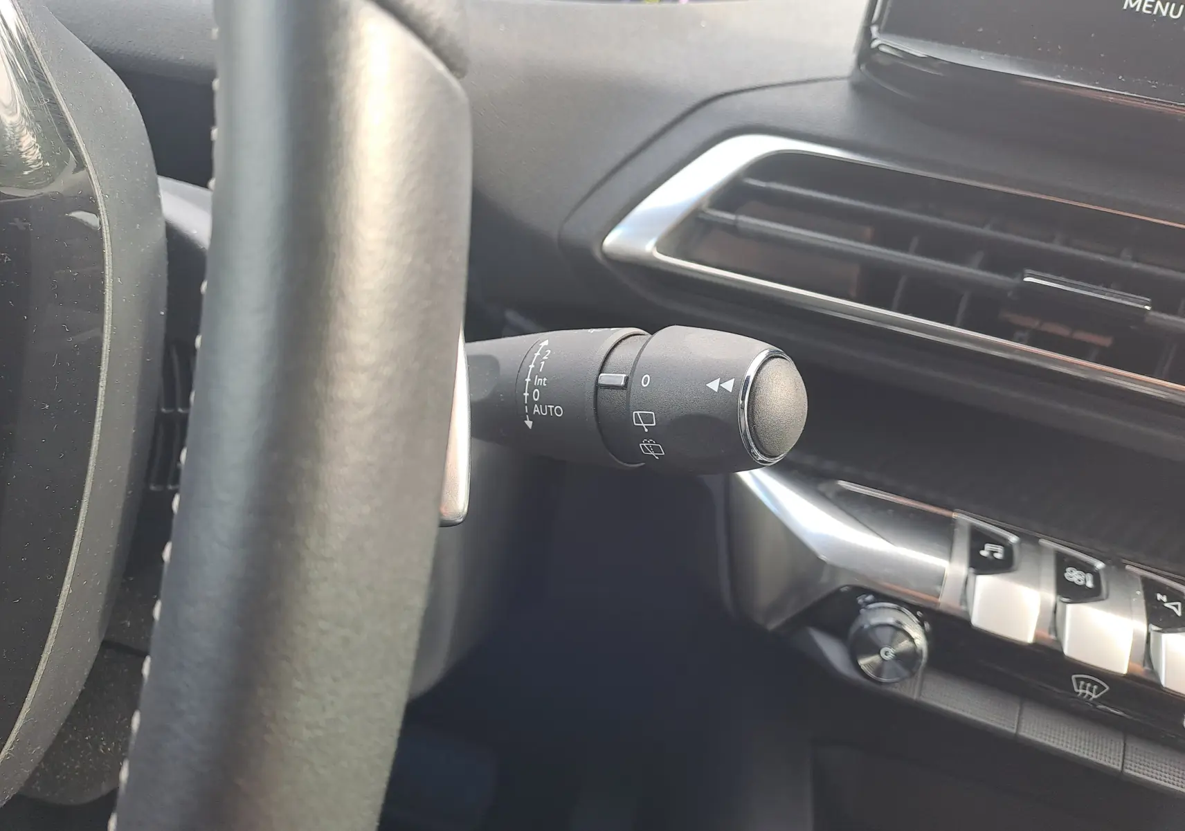 Gros plan sur la commande d'essuie-glace à gauche du volant dans l'habitacle gris du Peugeot 3008 Hybrid 2024.
