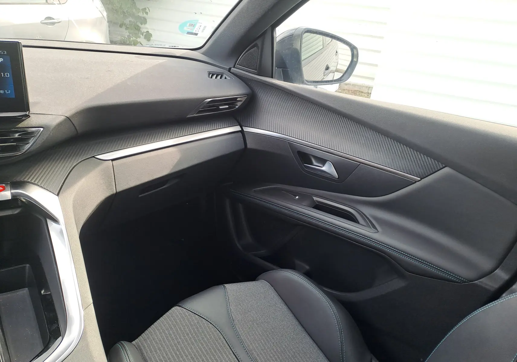 Vue intérieure côté passager du Peugeot 3008 Hybrid 145 Allure Pack 2024, avec sellerie noire et finitions modernes.