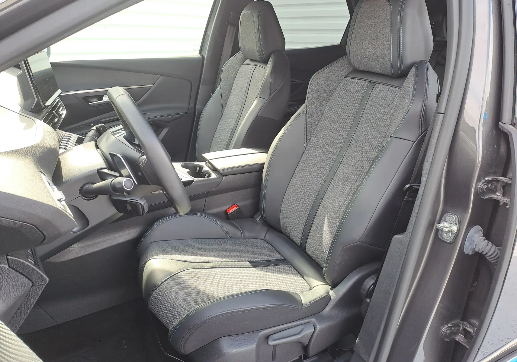 Vue intérieure côté conducteur du Peugeot 3008 Hybrid 145 Allure Pack 2024, sièges bi-matière gris et noir.