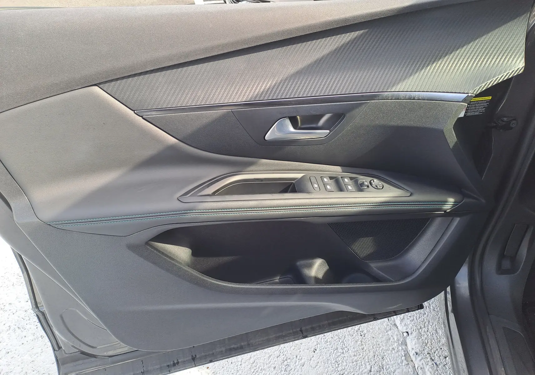 Porte avant gauche du Peugeot 3008 Hybrid gris platinium, avec commandes de vitres et poignée intégrée.