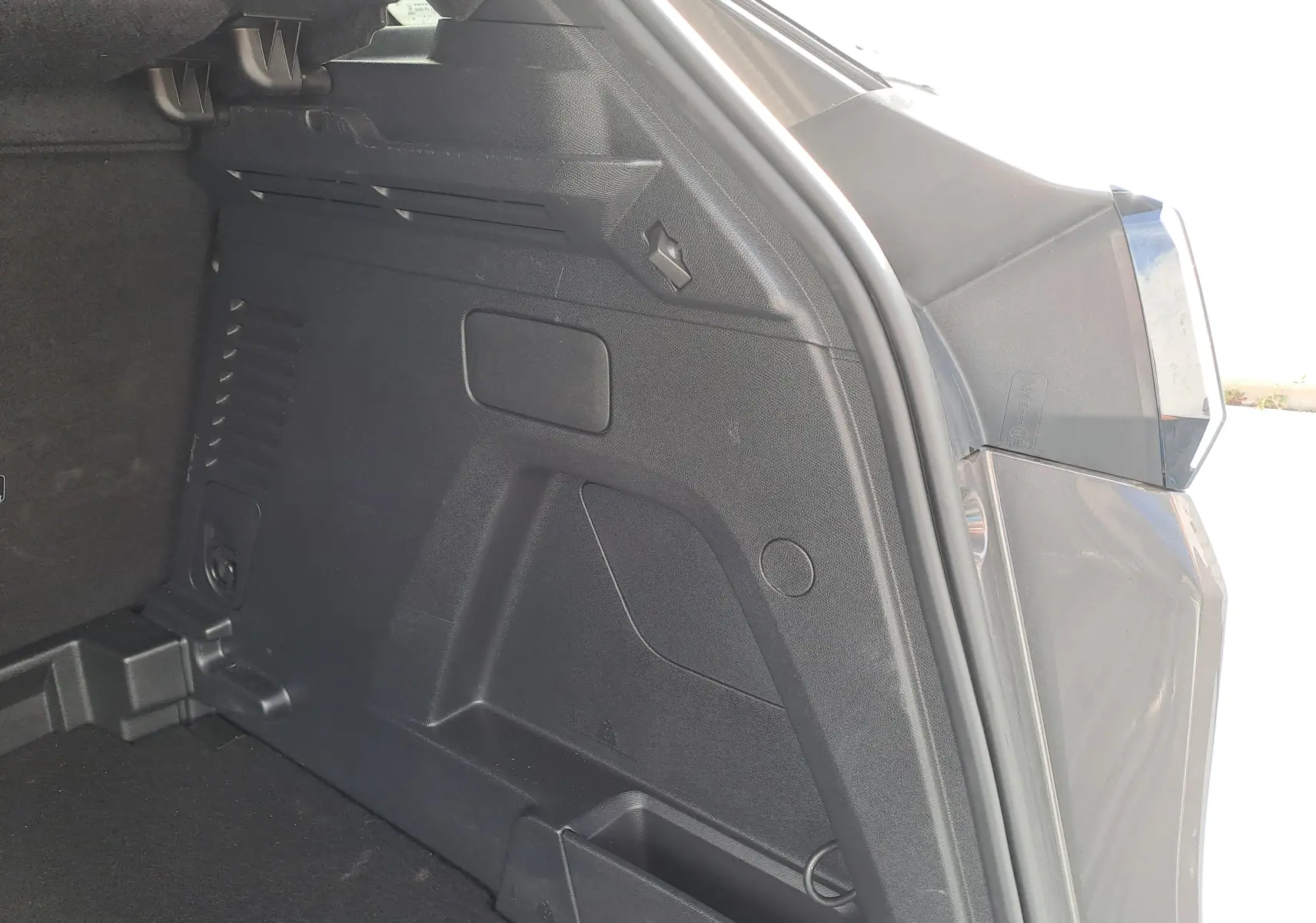 Vue rapprochée de l'intérieur du coffre côté droit d'un Peugeot 3008 Hybrid gris platinium 2024.