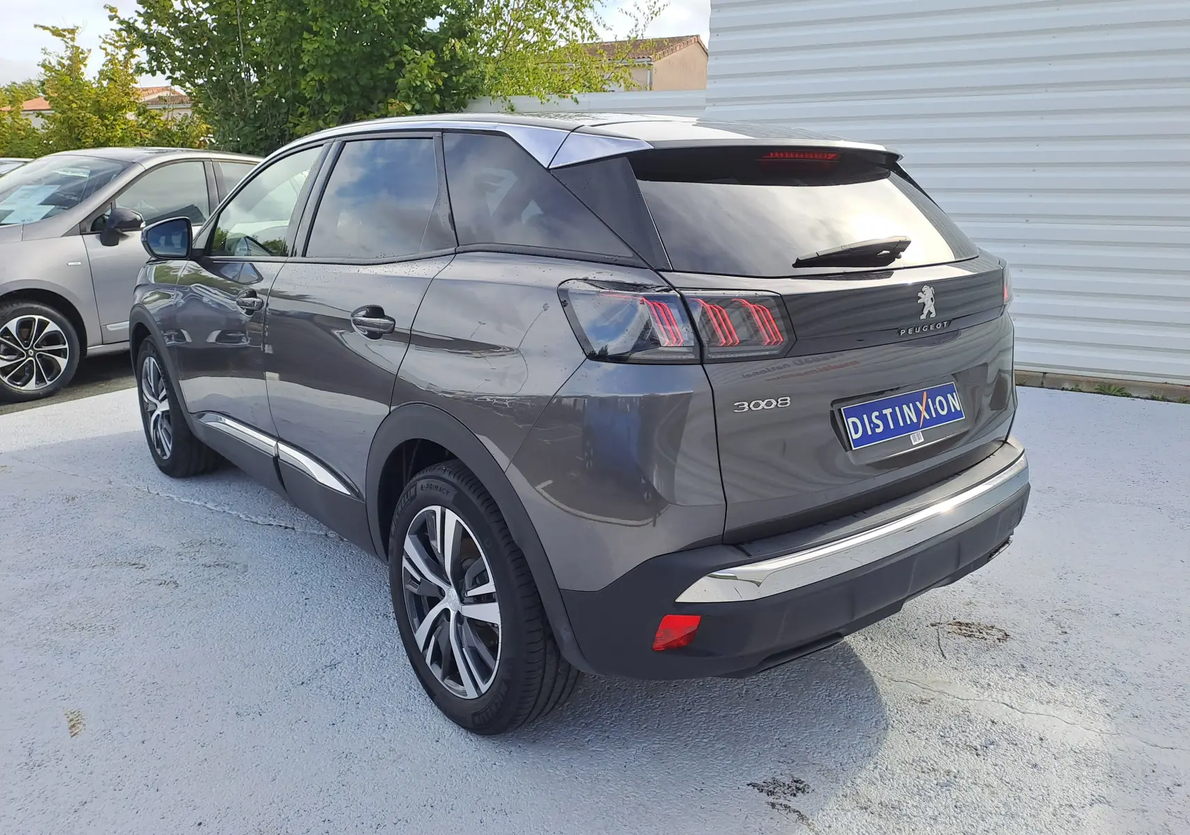 Vue 3/4 arrière droite d'un Peugeot 3008 gris platinium avec feux arrière à trois griffes et jantes alliage.