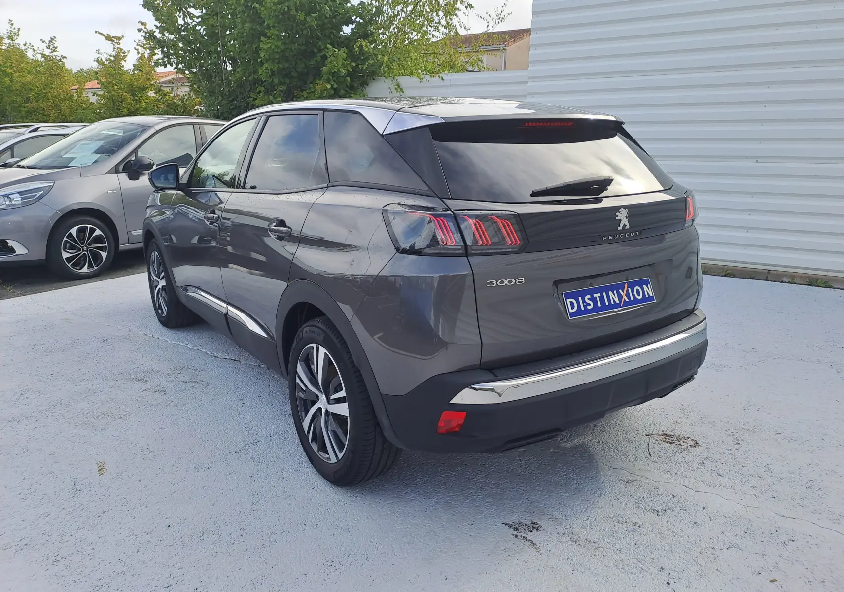 Peugeot 3008 gris platinium en vue 3/4 arrière droit, avec feux arrière à griffes et jantes alliage bicolores.