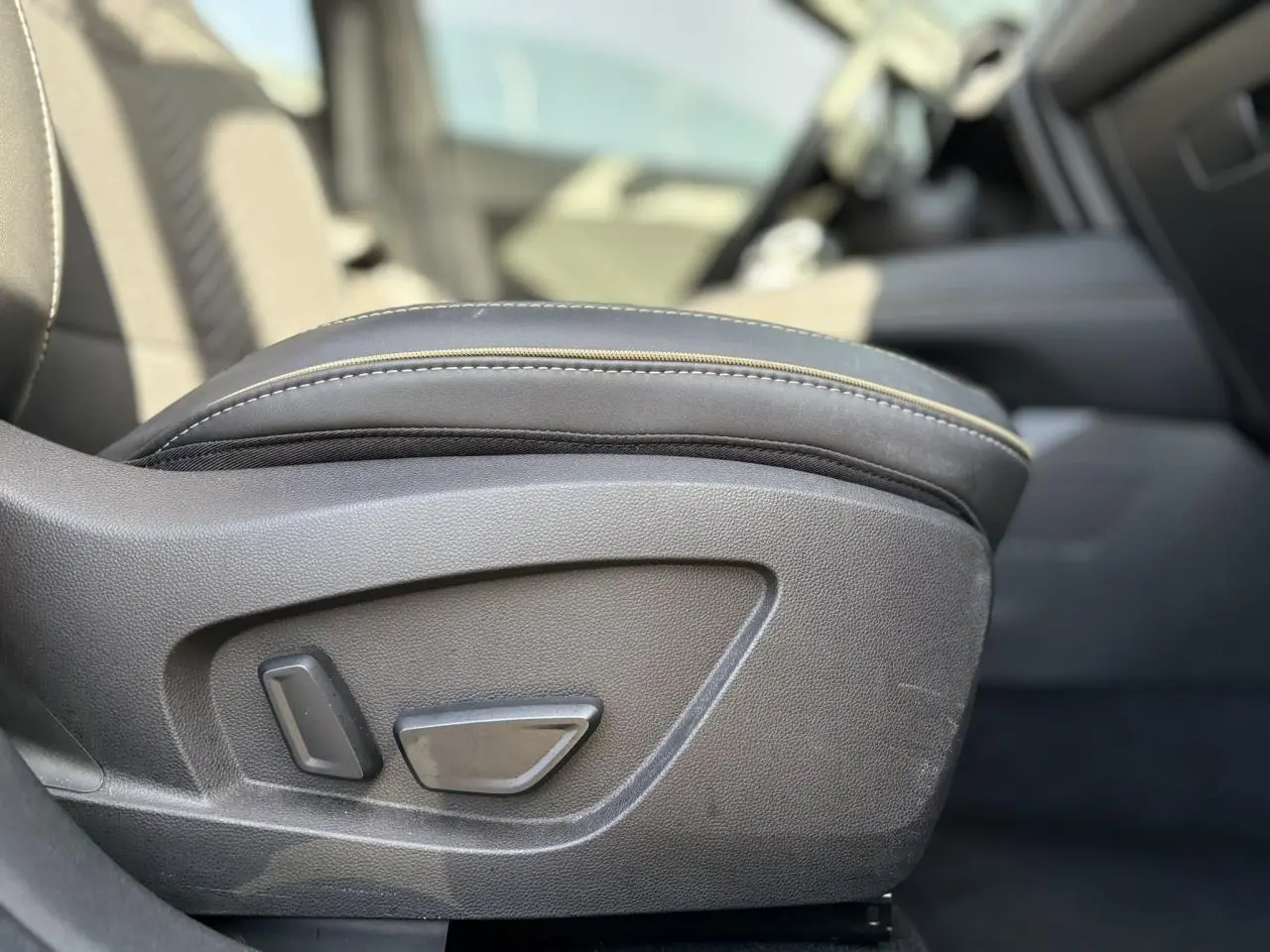 Détail du réglage électrique du siège avant en cuir noir dans l'habitacle d'une Renault SYMBIOZ gris Cassiopée.