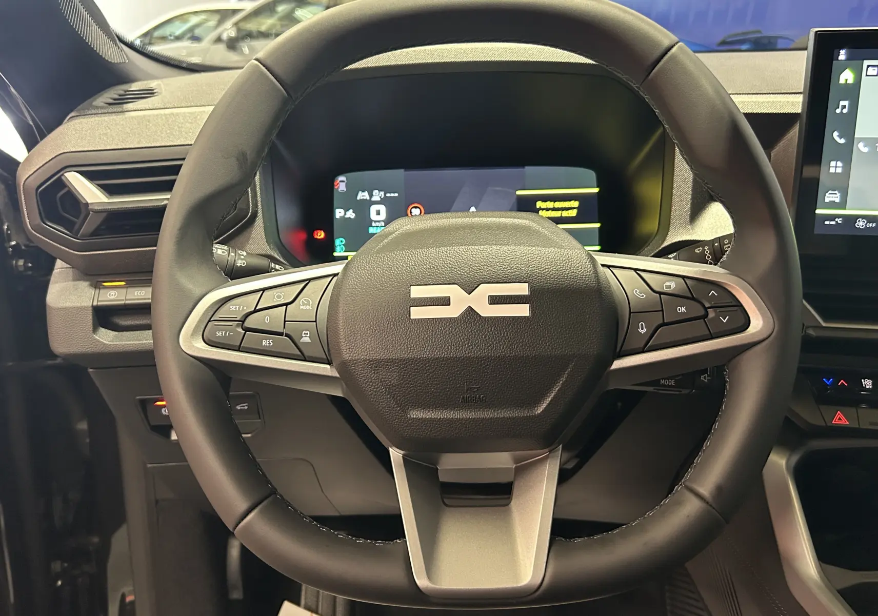 Vue rapprochée du volant multifonction noir du Dacia Bigster 2026 avec tableau de bord digital et écran tactile.