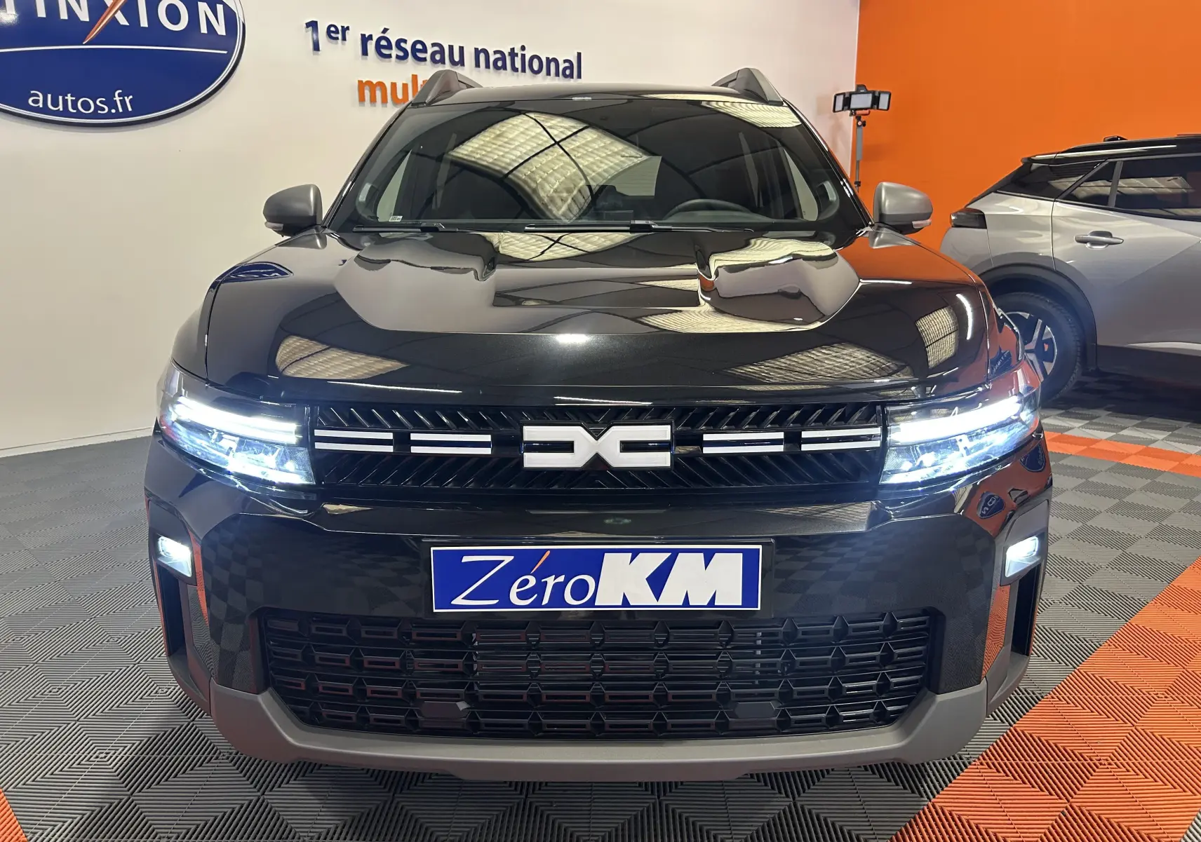 Vue avant frontale du Dacia Bigster noir nacré avec calandre distinctive et phares LED allumés en showroom.