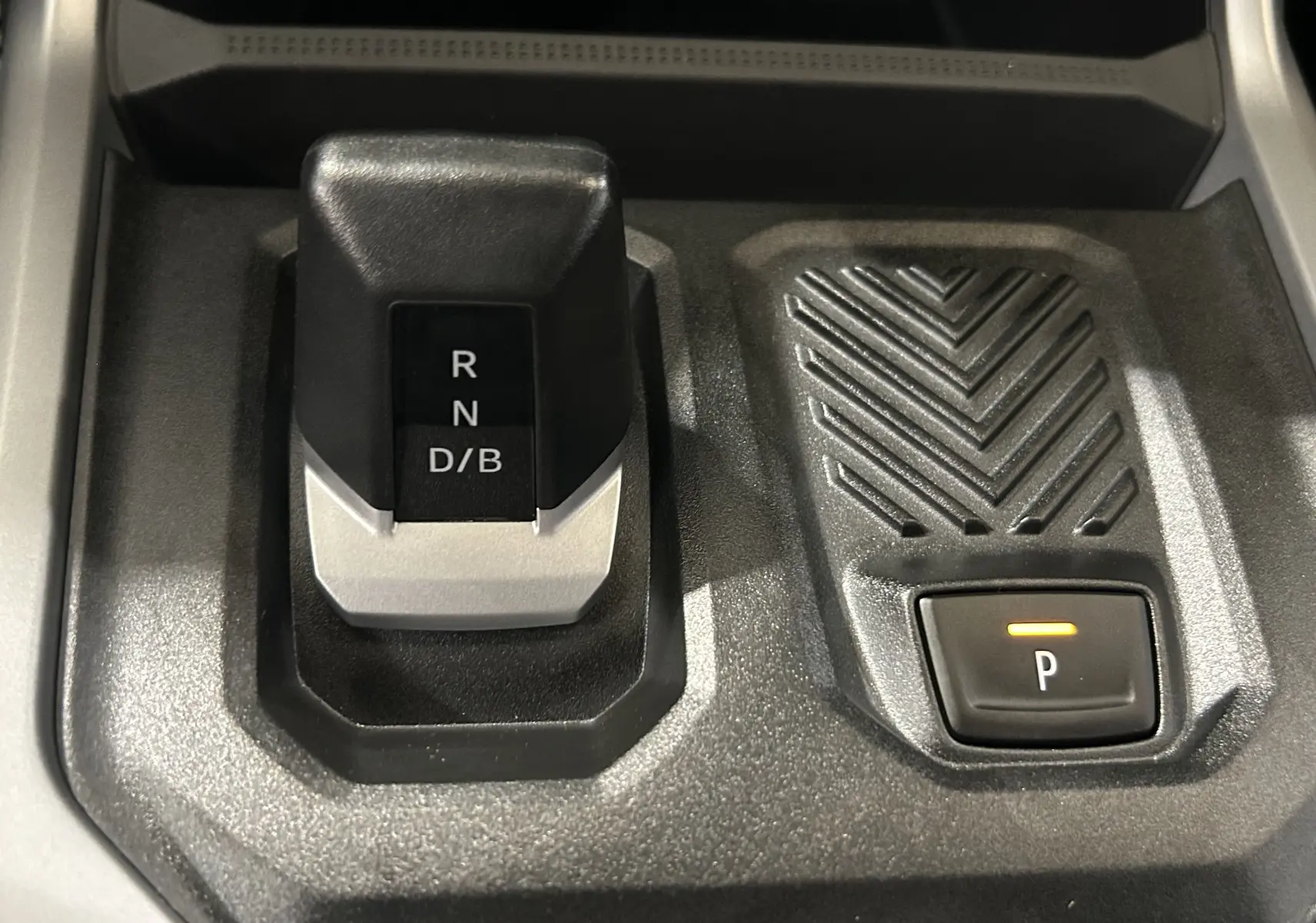 Gros plan sur la commande de boîte automatique et bouton de parking du Dacia Bigster 1.8 Hybrid 155, intérieur noir.