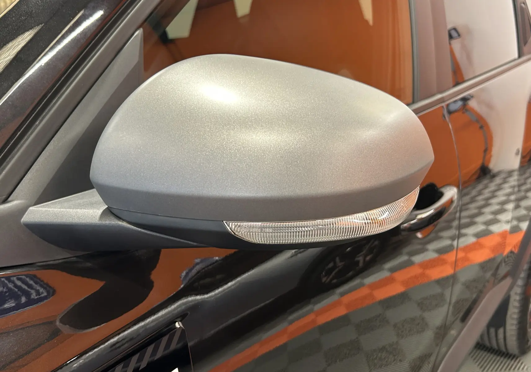 Gros plan sur le rétroviseur gris mat côté conducteur du Dacia Bigster noir nacré, avec clignotant intégré.