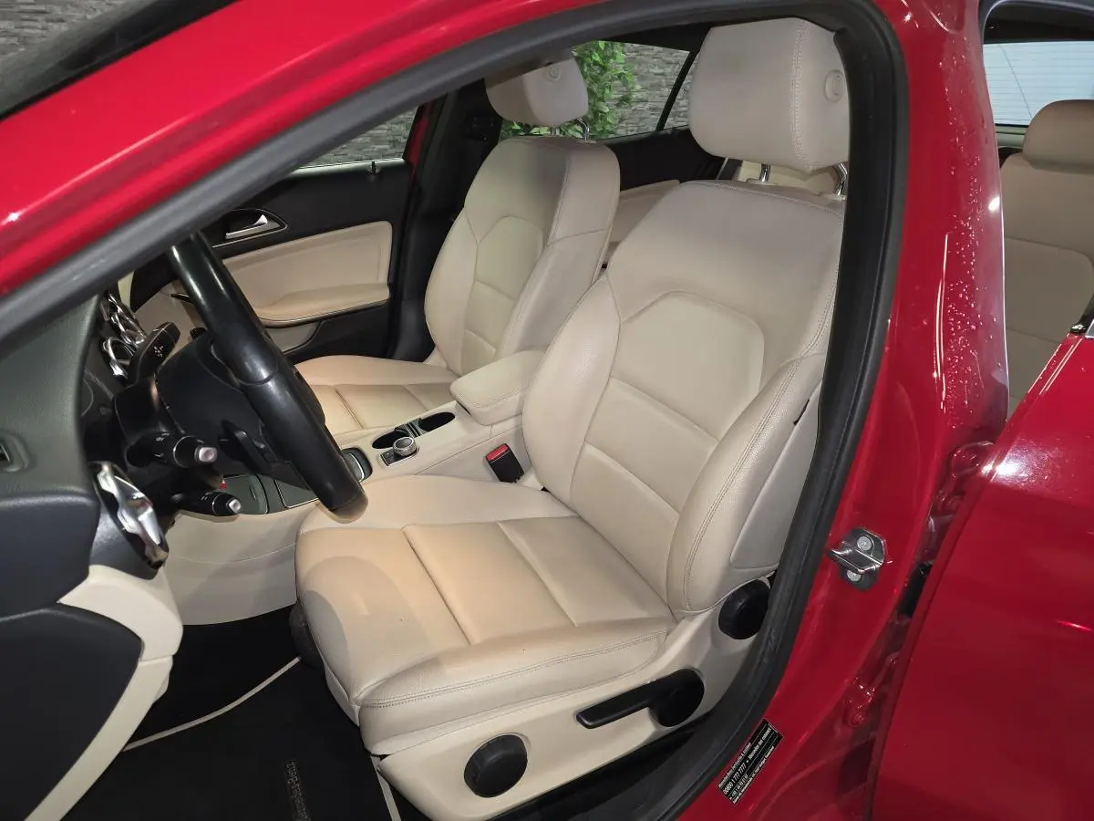 Vue intérieure côté conducteur du Mercedes GLA 200 d rouge, sièges avant en similicuir beige clair.