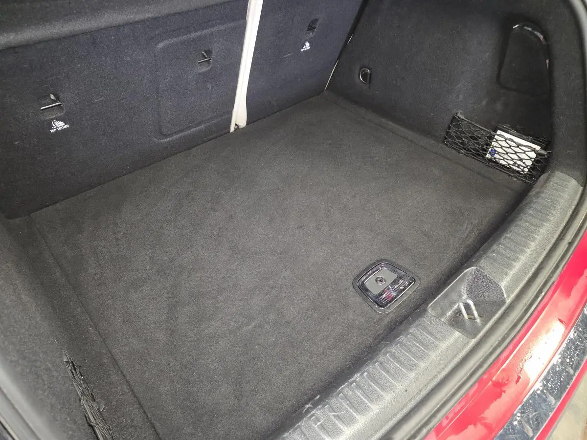 Vue plongeante sur le coffre spacieux et propre d’un Mercedes GLA 200 d rouge avec filet de rangement latéral.