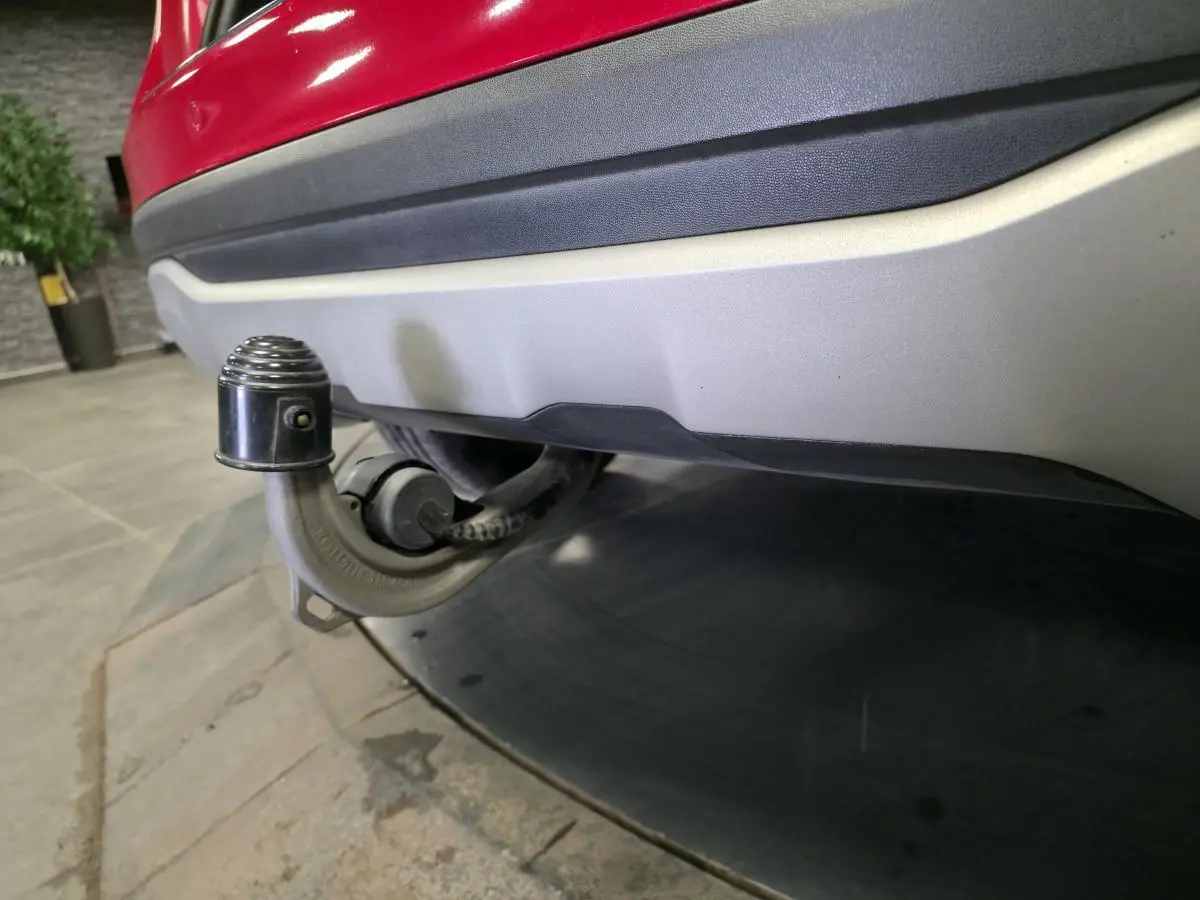 Gros plan sur l'attelage rabattable sous le pare-chocs arrière rouge d'un Mercedes GLA 200 d Inspiration.
