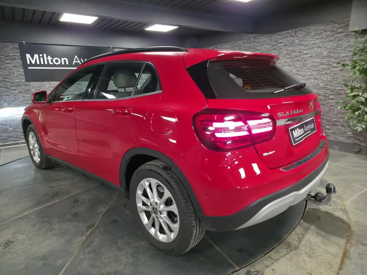 Vue 3/4 arrière droite d'un Mercedes GLA 200 d rouge avec attelage rabattable et jantes alliage 17 pouces.