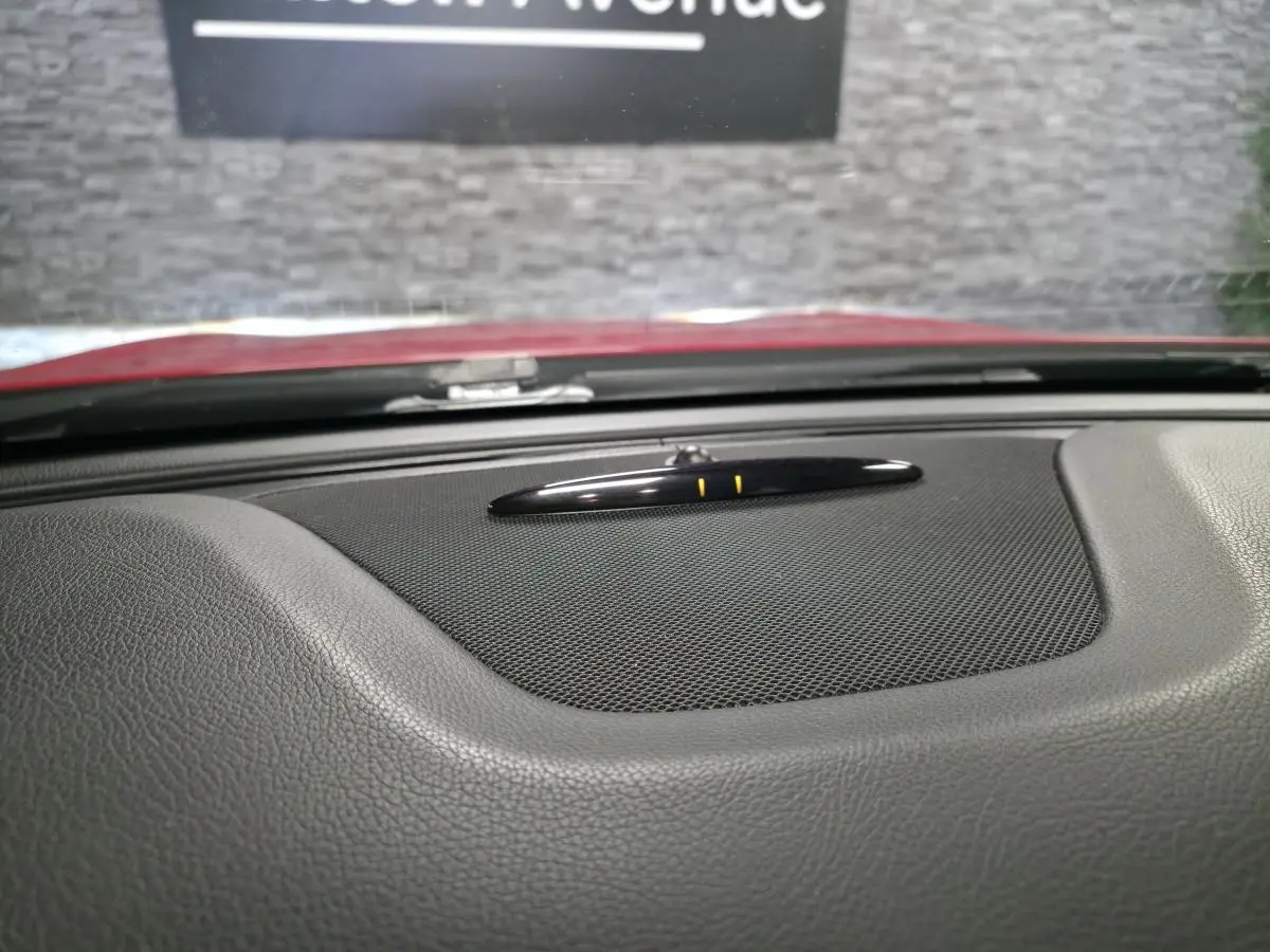 Gros plan sur le tableau de bord noir texturé du Mercedes GLA 200 d rouge, avec haut-parleur central et capteur au centre.