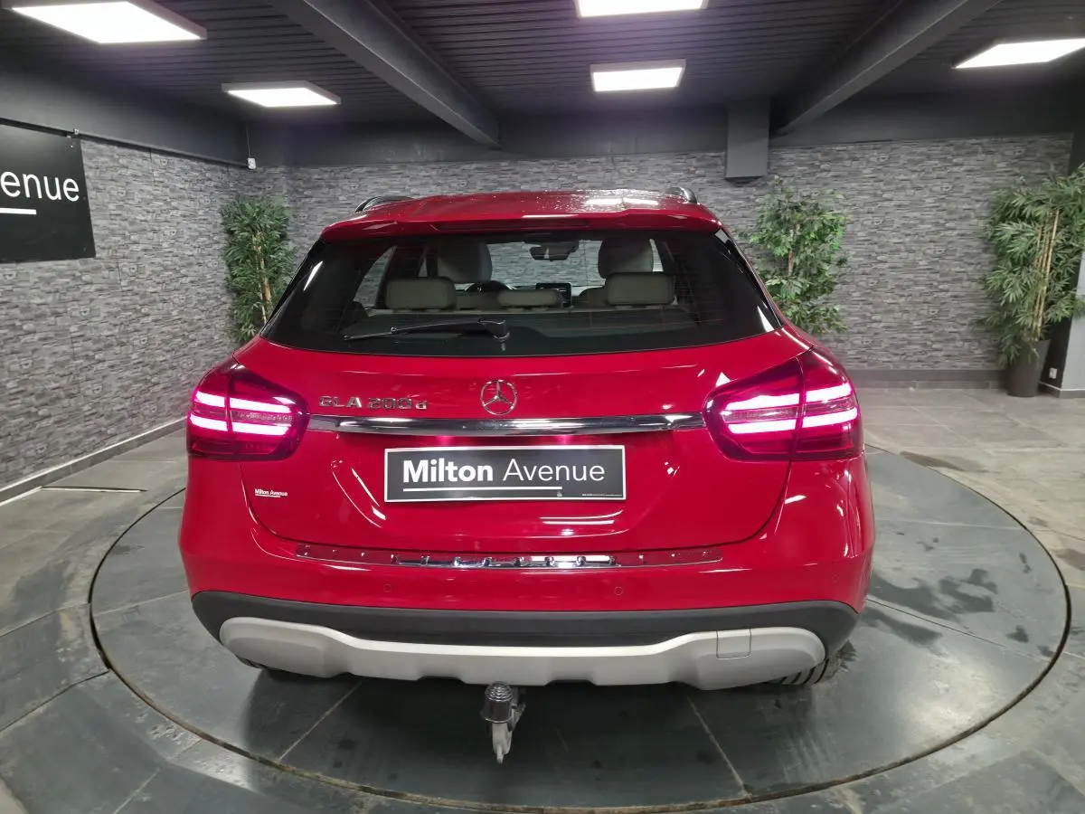 Vue arrière d'un Mercedes GLA 200 d rouge avec attelage rabattable et feux LED allumés dans un showroom.