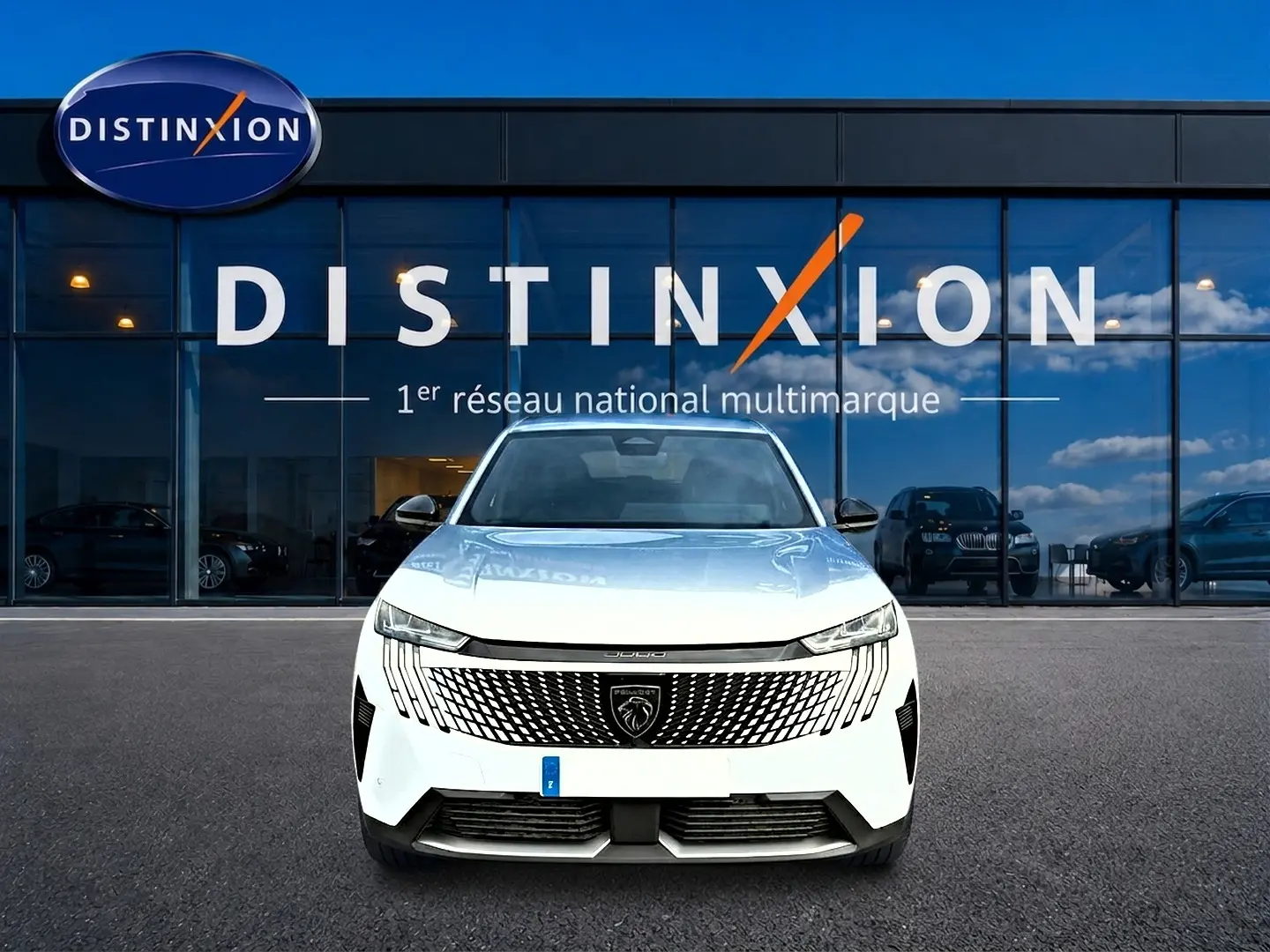 Vue frontale d'un Peugeot 3008 blanc 2025 avec calandre distinctive et logo lion visible devant un showroom Distinxion.
