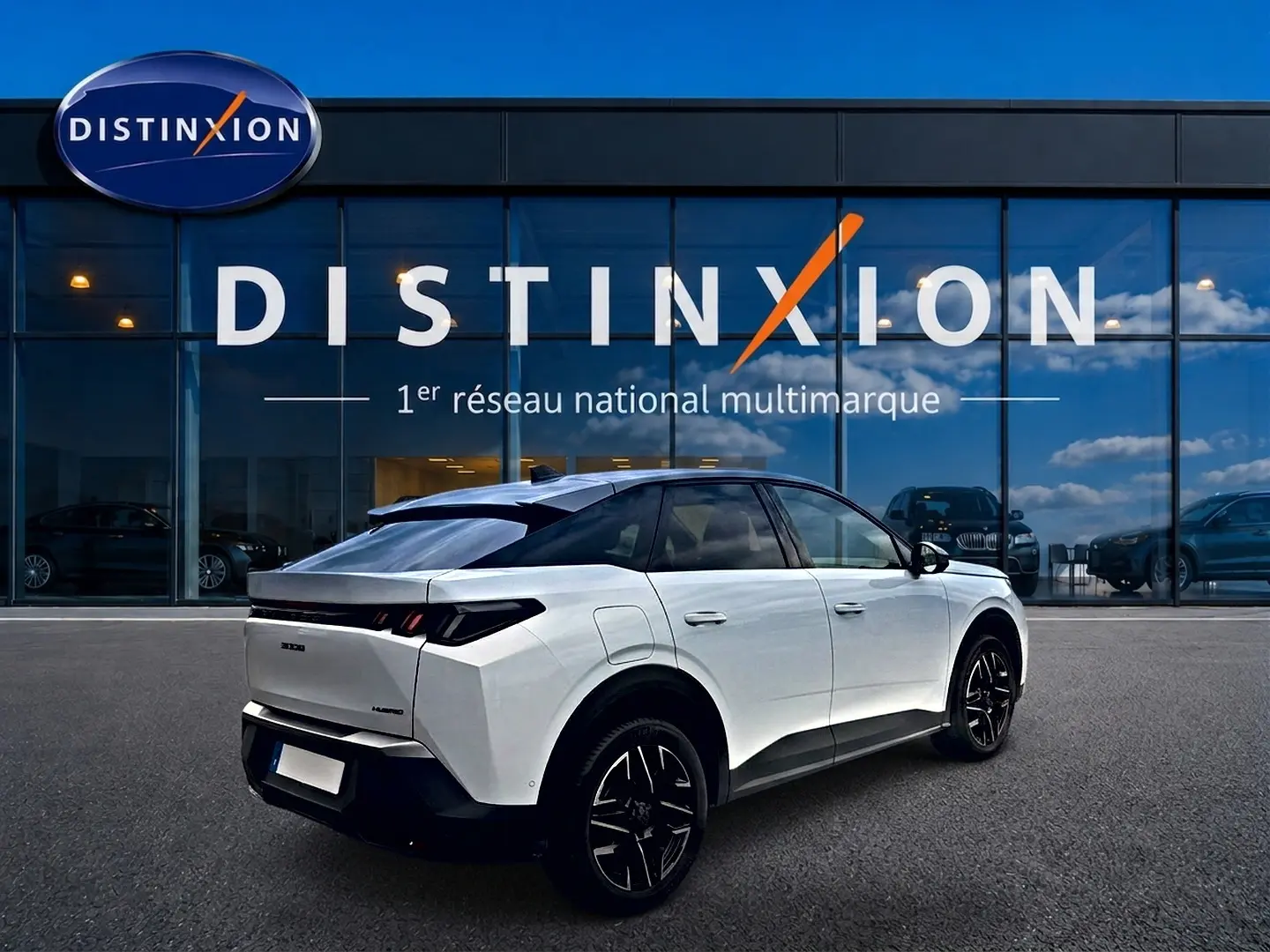 Vue 3/4 arrière droite d’un Peugeot 3008 blanc avec toit noir, jantes alu noires et feux arrière LED, devant une vitrine Distinxion.