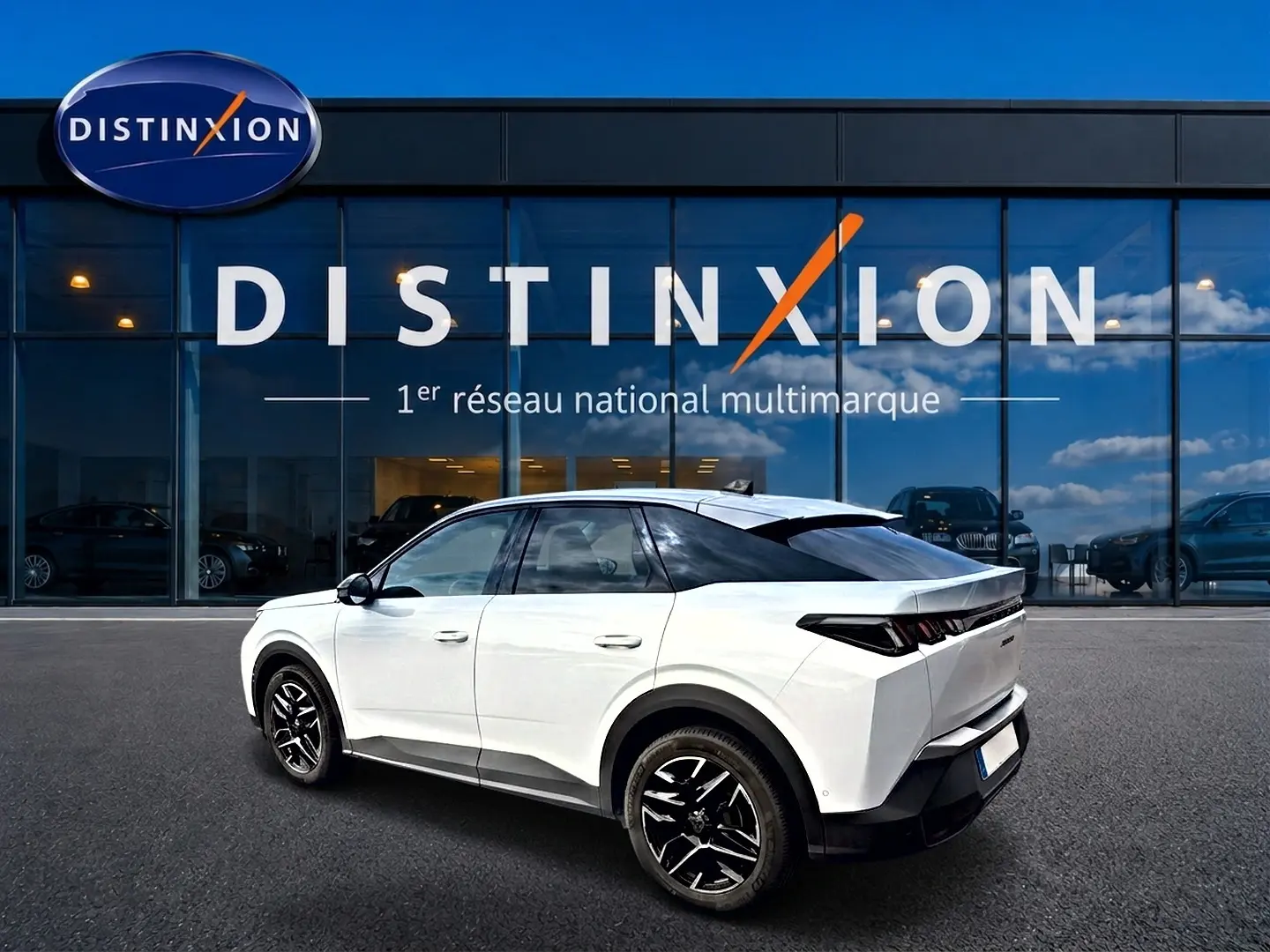 Vue 3/4 arrière droite d’un Peugeot 3008 blanc 2025 avec jantes alu noires devant une vitrine Distinxion.