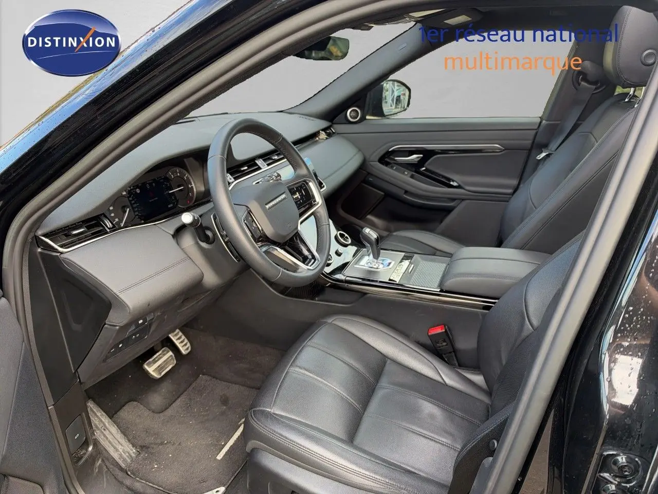 Vue intérieure côté conducteur du Range Rover Evoque 2023 noir Santorini, avec sièges cuir et tableau de bord moderne.