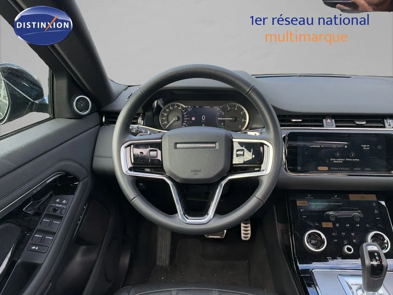 Vue intérieure centrée sur le volant cuir noir du Range Rover Evoque P300e avec tableau de bord et console tactile.