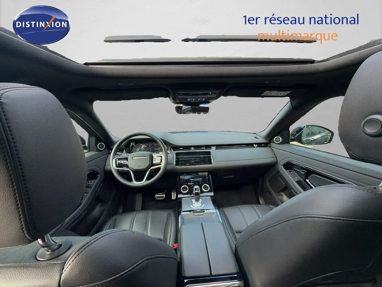 Vue intérieure avant du Range Rover Evoque 2023 en cuir noir, avec tableau de bord moderne et toit panoramique.