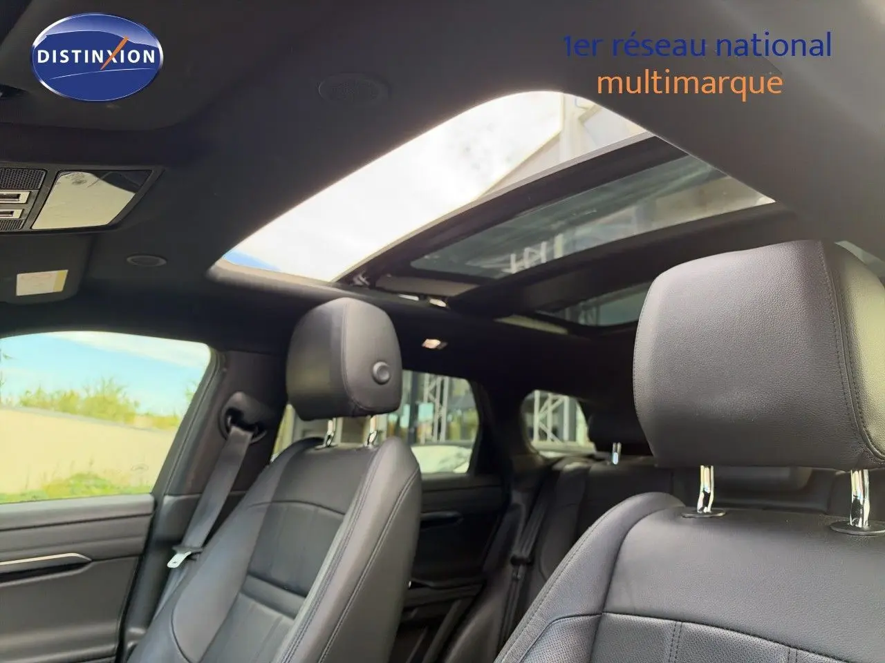 Intérieur du Range Rover Evoque 2023 en cuir noir, vue sur les sièges avant et toit ouvrant panoramique.